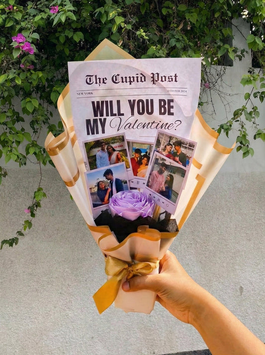 Bouquet of flowers wrapped with 'The Cupid Post' newspaper asking 'Will You Be My Valentine?' held by a hand.